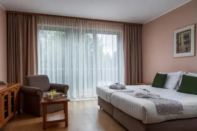 a bedroom with a bed and a chair and a large window at Grand Hotel BELLEVUE in Pohorje