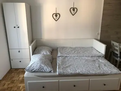 a white bed with two pillows and hearts on the wall at Apartma Vintage Bohinj in Bohinj