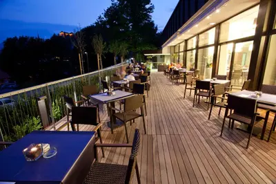 a restaurant with tables and chairs on a deck at Hotel Astoria Superior in Bled