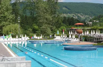 a large swimming pool with chairs and umbrellas at Hotel Kristal - Terme Krka in Dolenjske Toplice