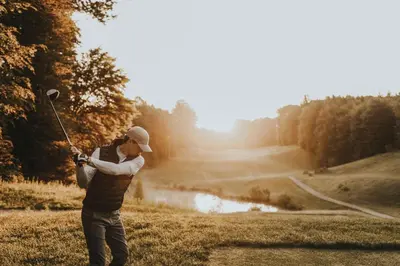 a man swinging a golf club at a pond at Hotel Sport - Terme Krka in Otočec