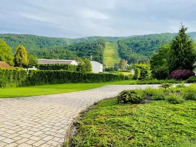 a brick driveway in a garden with a hill in the background at Hotel Pohorje in Maribor