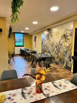 a restaurant with tables and chairs and a large mural at Hotel Pohorje in Maribor