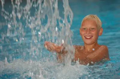 a young boy is playing in the water at Terme Zrece - Hotel Vital in Zreče