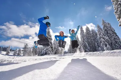 a group of three people jumping in the snow at Terme Zrece - Hotel Vital in Zreče