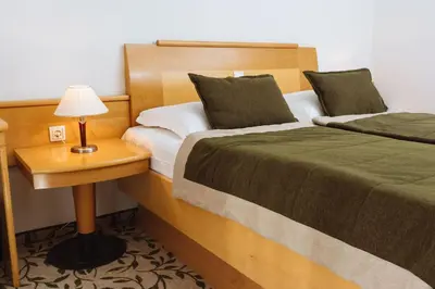 a bedroom with two beds and a table with a lamp at Terme Zrece - Hotel Vital in Zreče