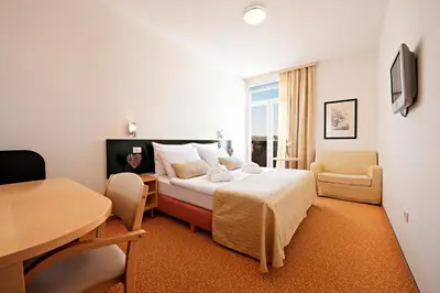 a hotel room with a bed and a table and chairs at Hotel Radin, Radenci Spa Resort - Sava Hotels & Resorts in Radenci