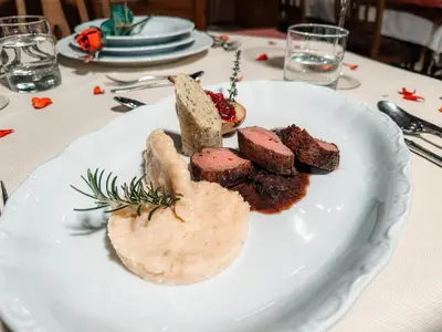 a white plate with meat and bread on a table at Hotel Oskar Zaplata in Preddvor