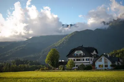 a house in a field with mountains in the background at Hotel Oskar Zaplata in Preddvor