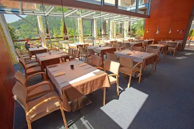 a restaurant with wooden tables and chairs and windows at Hotel Creina in Kranj