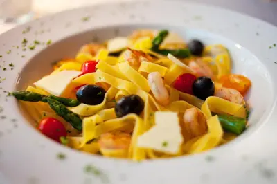 a white bowl of pasta with vegetables and cheese at Hotel Creina in Kranj