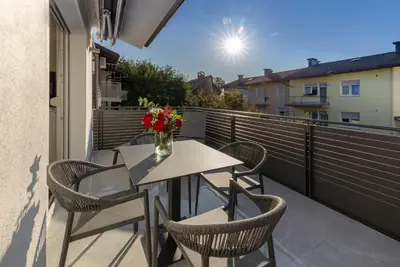 a table and chairs on a balcony with a vase of flowers at Deluxe Apartma Jana in Ljubljana