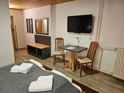 a room with a tv and a table and chairs at Hotel Gasperin Bohinj in Bohinj