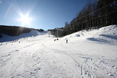 a group of people skiing down a snow covered slope at Pohorje Village Wellbeing Resort - Wellness & Spa Hotel Bolfenk in Pohorje