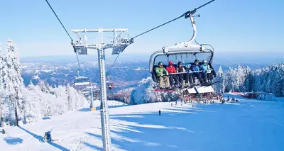 a group of people sitting on a ski lift at Pohorje Village Wellbeing Resort - Wellness & Spa Hotel Bolfenk in Pohorje