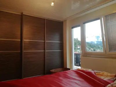 a bedroom with wooden cabinets and a bed with a window at Poldas apartments in Poljane nad Škofjo Loko
