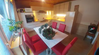a kitchen with a dining table and red chairs at Poldas apartments in Poljane nad Škofjo Loko