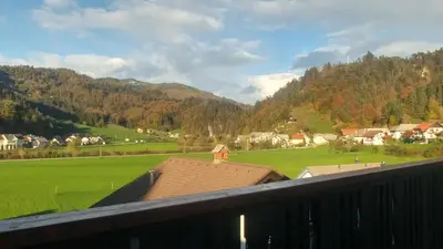 a balcony with a view of a green field and mountains at Poldas apartments in Poljane nad Škofjo Loko