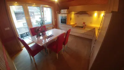 a kitchen with a dining room table and red chairs at Poldas apartments in Poljane nad Škofjo Loko