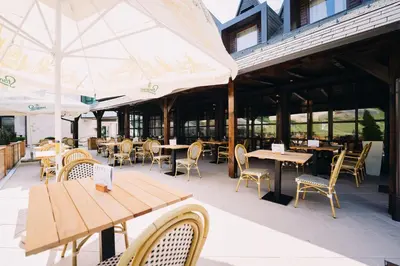 an outdoor restaurant with tables and chairs and umbrellas at Hotel Arena Maribor in Maribor