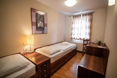 a small bedroom with two beds and a desk at Hotel Dvor Jezersek Brnik in Cerklje na Gorenjskem