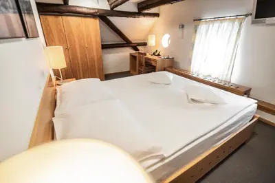 a large white bed in a room with a window at Hotel Dvor Jezersek Brnik in Cerklje na Gorenjskem
