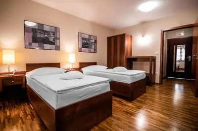 two beds in a room with wooden floors at Hotel Dvor Jezersek Brnik in Cerklje na Gorenjskem