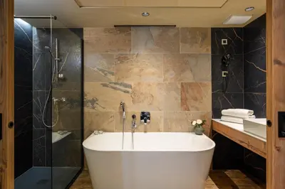 a bathroom with a tub and a glass shower at Postojna Cave Hotel Jama in Postojna