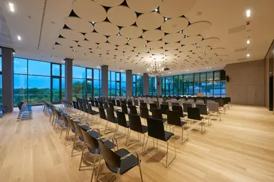 a large room with rows of chairs and a chandelier at Postojna Cave Hotel Jama in Postojna