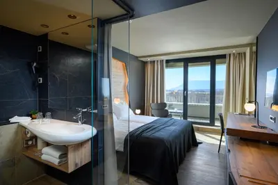 a bathroom with a bed and a sink and a mirror at Postojna Cave Hotel Jama in Postojna