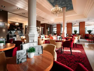 a restaurant with tables and chairs and a chandelier at Hotel Evropa in Celje