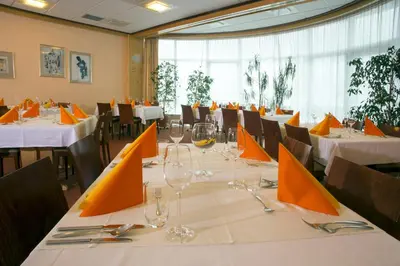 a dining room with tables and chairs with orange napkins at Hotel Krek Superior in Lesce
