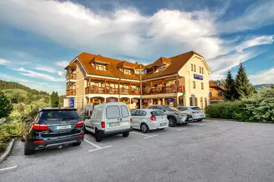 a large building with cars parked in a parking lot at Garni Hotel Zvon in Zreče