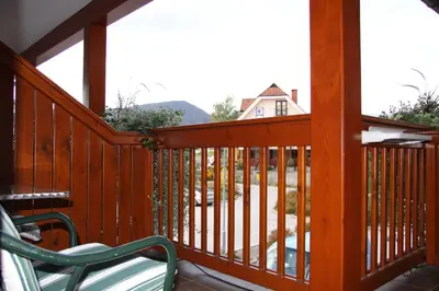 a wooden deck with a bench and a house at Garni Hotel Zvon in Zreče