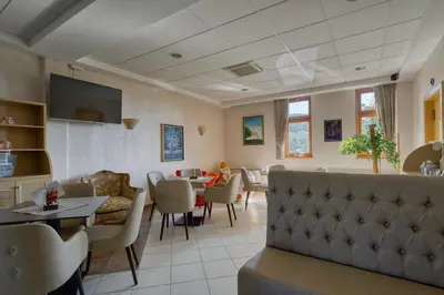 a living room with a couch and a table and chairs at Garni Hotel Zvon in Zreče