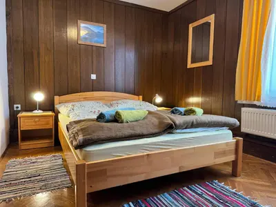 a bedroom with a bed with a wooden wall at Pension Cerkovnik in Bohinj