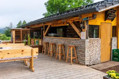 a bar with stools in front of a building at Pension Cerkovnik in Bohinj