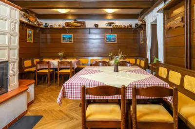 a dining room with tables and chairs and wooden walls at Pension Cerkovnik in Bohinj