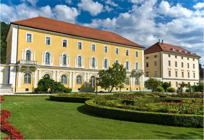 a large yellow building with a red roof and a garden at Grand Hotel Rogaska in Rogaška Slatina