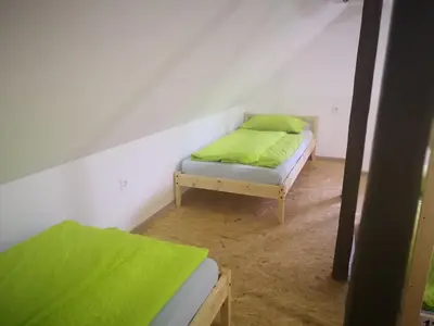 a small room with a bed with green sheets at Bus Station Beds in Bled