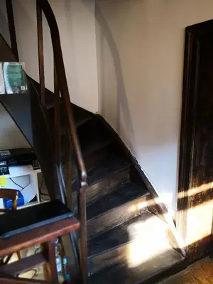 a stairway with a wooden chair and a stair case at Bus Station Beds in Bled