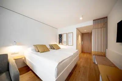 a bedroom with a large white bed and a chair at Hotel Termal - Terme 3000 - Sava Hotels & Resorts in Moravske Toplice