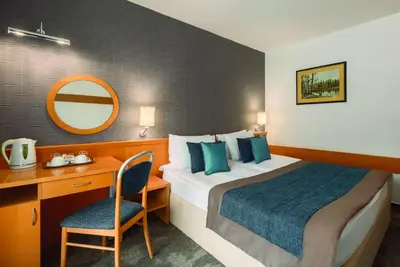 a hotel room with a bed and a desk and a mirror at Ramada Resort Kranjska Gora in Kranjska Gora