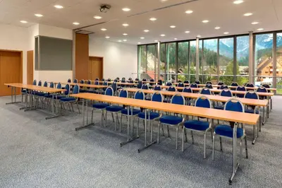 a conference room with tables and blue chairs at Ramada Resort Kranjska Gora in Kranjska Gora