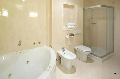 a bathroom with a tub and a toilet and a shower at Hotel Kompas in Kranjska Gora