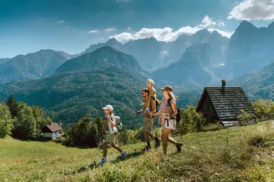 a group of people walking on a hill in the mountains at Hotel Kompas in Kranjska Gora