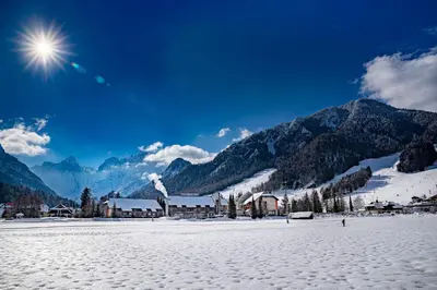 a snow covered field with a town and mountains at Hotel Kompas in Kranjska Gora