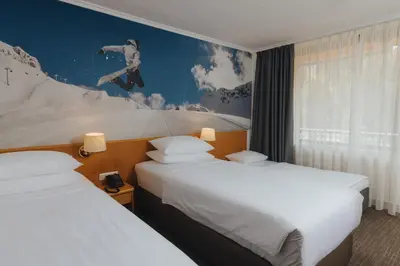 a hotel room with two beds and a mural at Hotel Kompas in Kranjska Gora