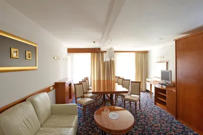 a hotel room with a waiting area with a table and chairs at Hotel Kompas in Kranjska Gora
