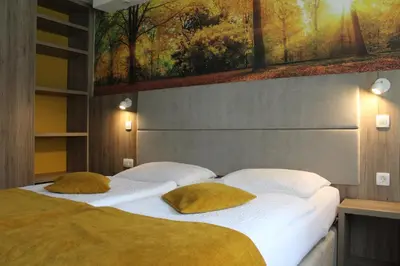 two beds in a bedroom with a painting on the wall at Hotel Alpina in Kranjska Gora